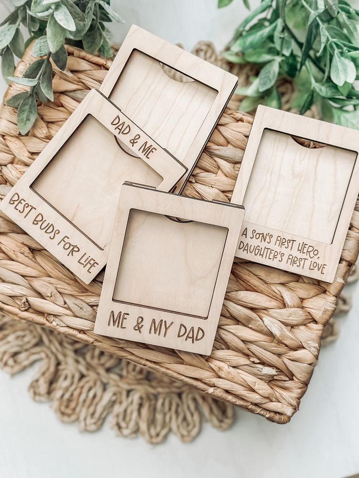 three wooden frames sitting on top of a wicker basket next to a potted plant