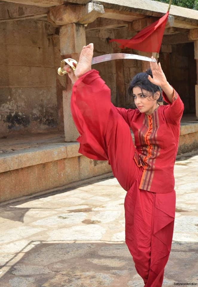 a woman in a red outfit is doing an acrobatic move with her hands