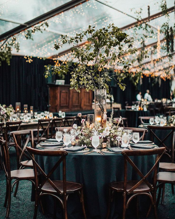 an outdoor tent with tables and chairs set up for dinner