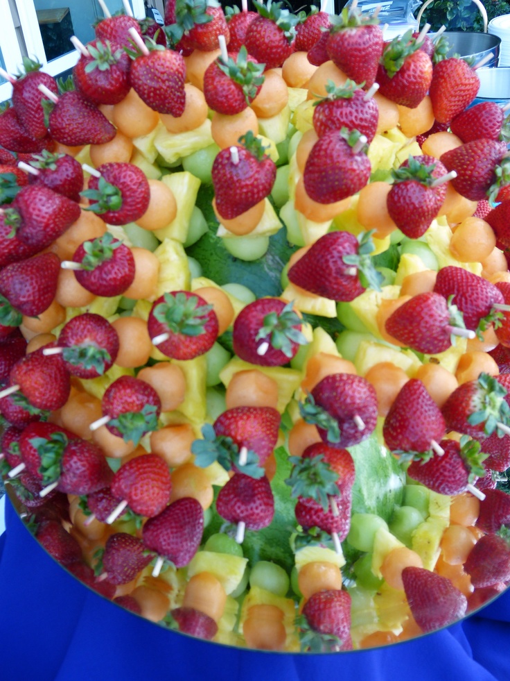 a large platter filled with lots of fruit on top of a blue table cloth