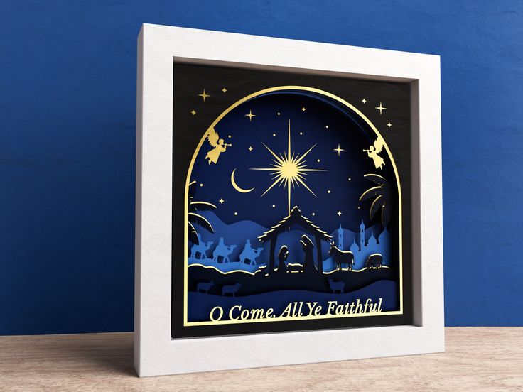 an illuminated christmas card with the nativity scene in blue and white, on a wooden table