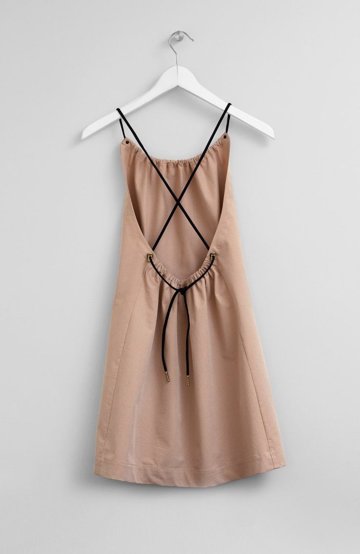 a tan dress hanging on a white hanger with black straps and an open back