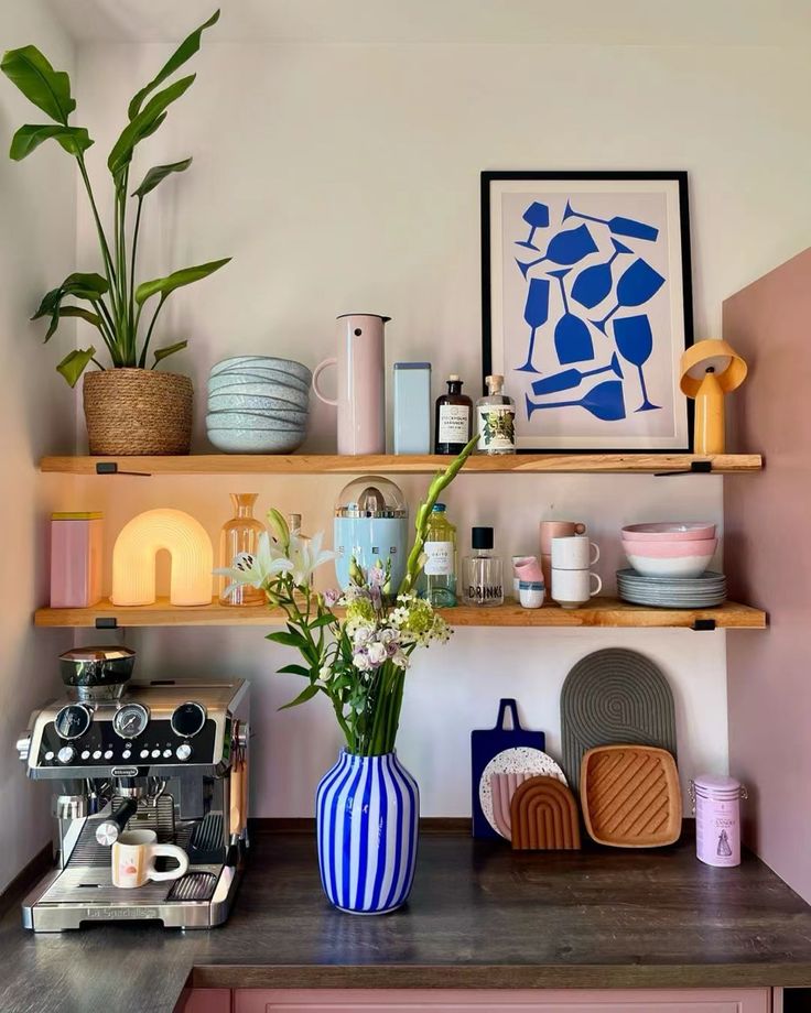 a kitchen with pink cabinets and shelves filled with dishes, vases and other items