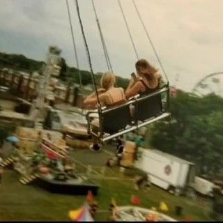 two people ride on a swing at an amusement park