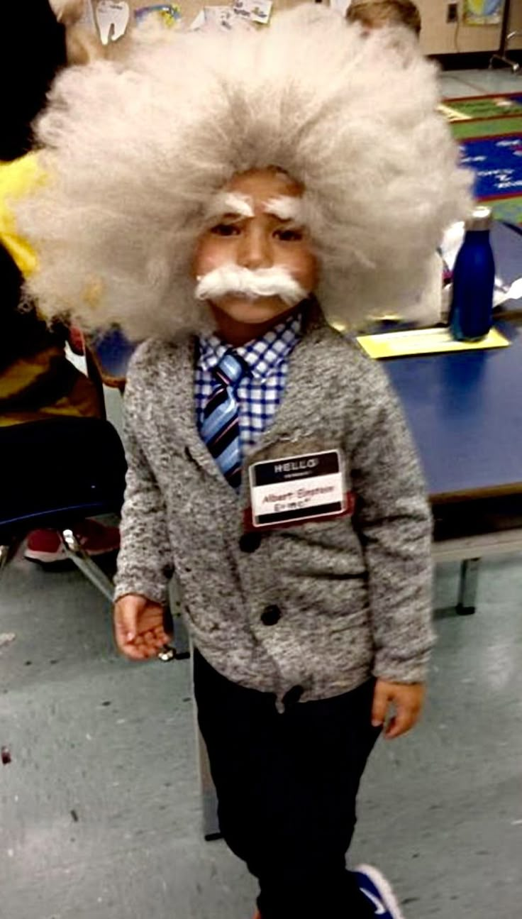 a young child wearing a wig and tie with a fake moustache on his face