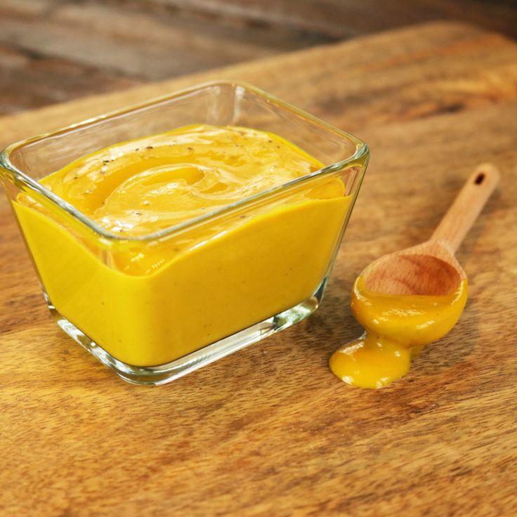 a small glass bowl filled with yellow liquid next to a wooden spoon