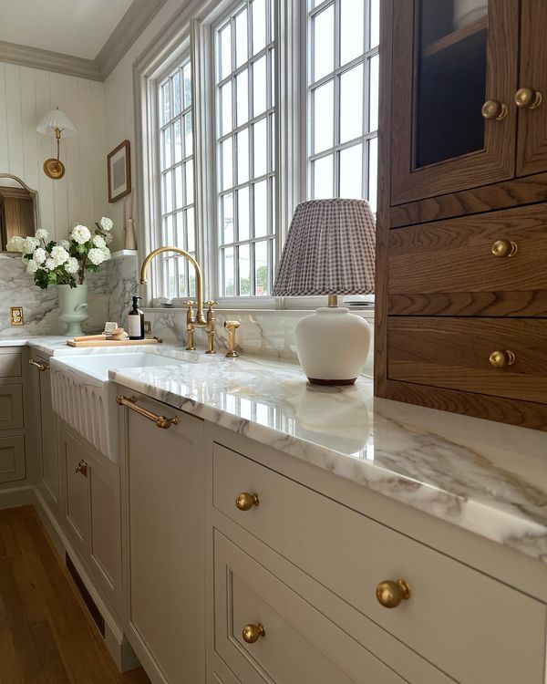 a large kitchen with marble counter tops and gold hardware on the handles, along with white cabinets