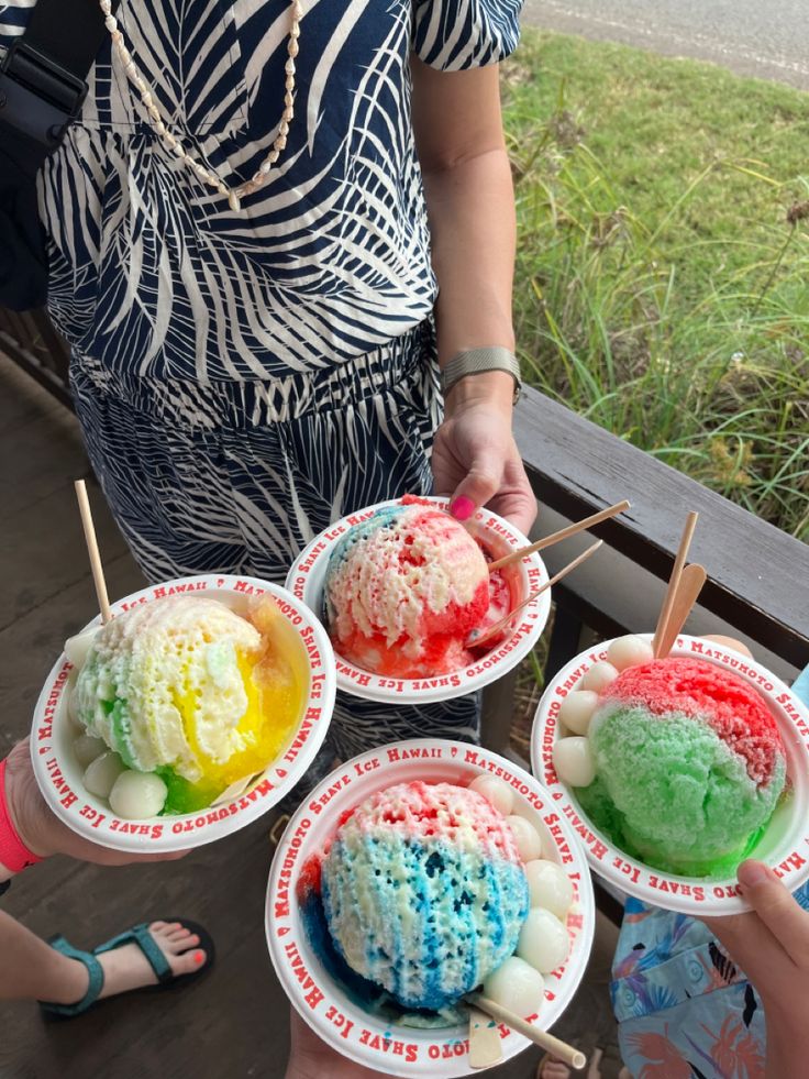 four people are holding bowls with different colored ice creams on them, and one person is eating an ice cream sundae