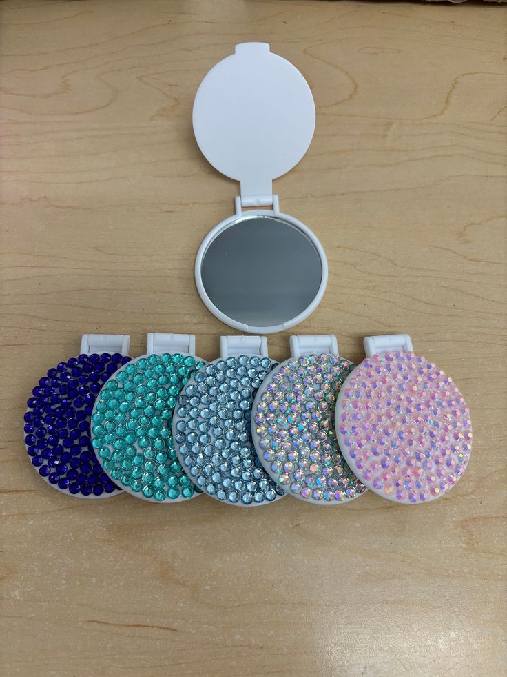 five round mirrors with different colors and sizes on a wooden table next to a mirror