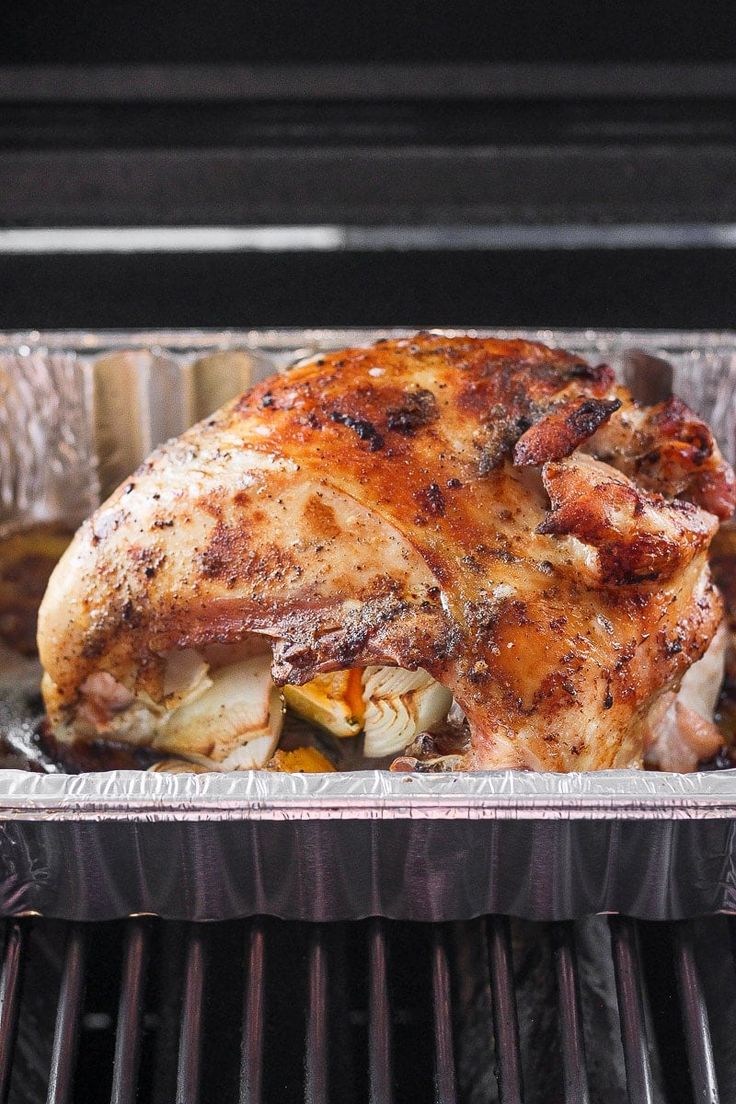 a close up of a chicken in a pan on an open grill with tin foil