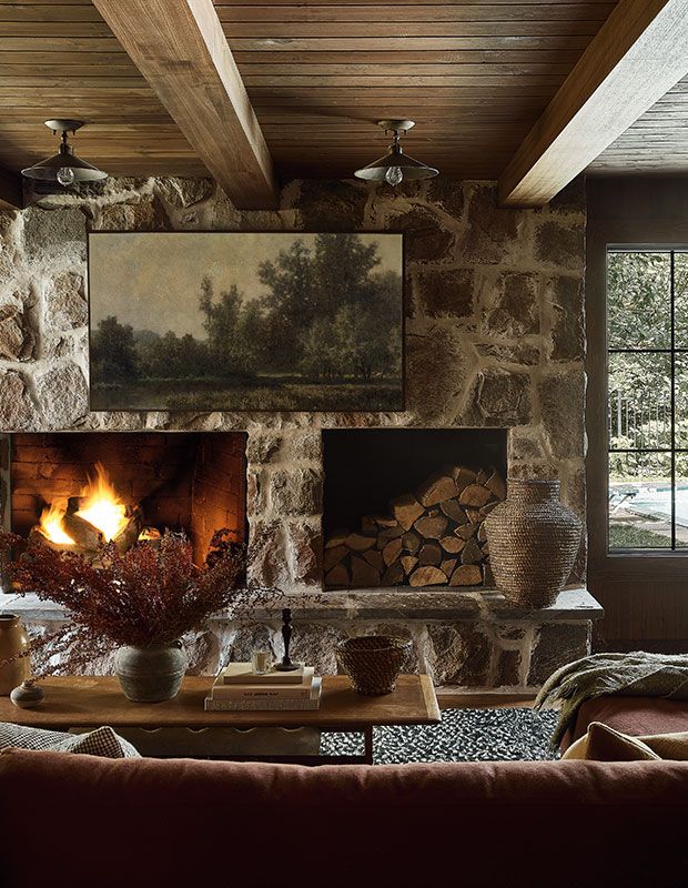 a living room filled with furniture and a fire place in front of a stone wall