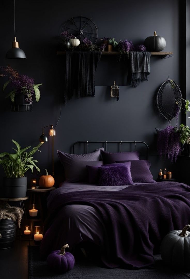 a bed with purple sheets and pillows in a dark room filled with pumpkins, potted plants and candles