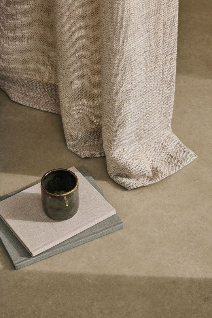 a cup and napkin on the floor next to a curtain