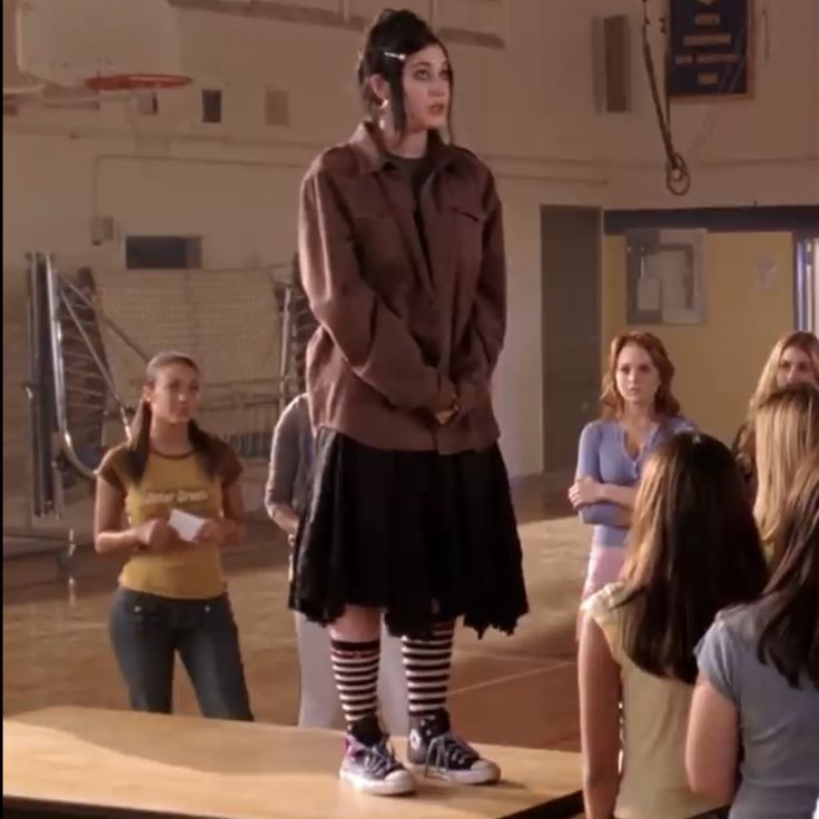 a woman standing on top of a wooden table next to other people in a room