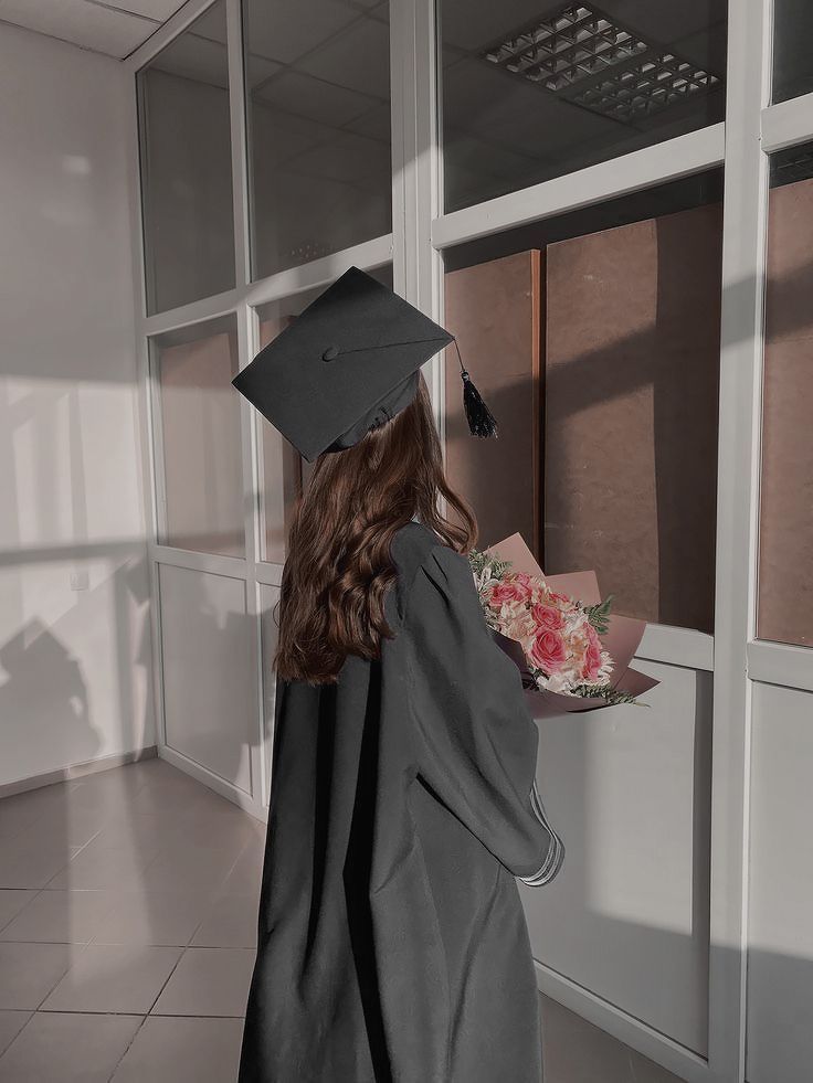 a woman wearing a graduation cap and gown is holding a tray with food in it