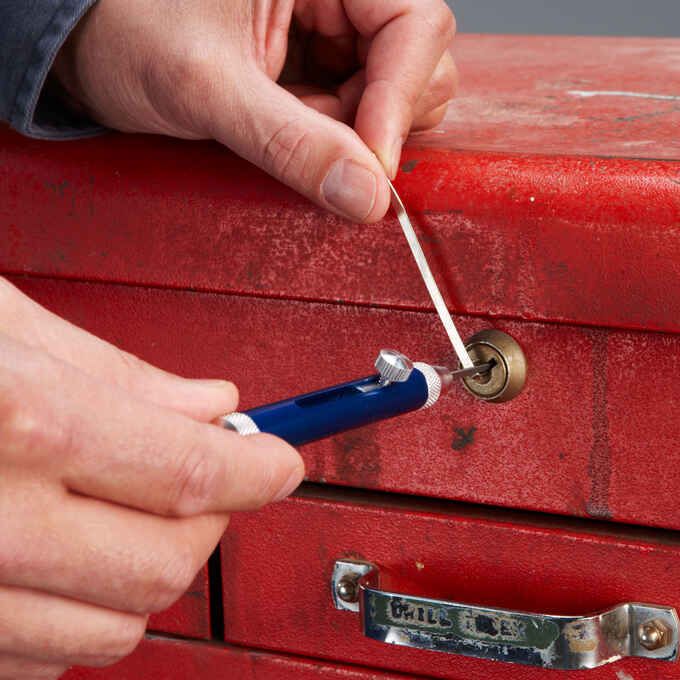 a person is opening a red box with a blue handle and a small screwdriver