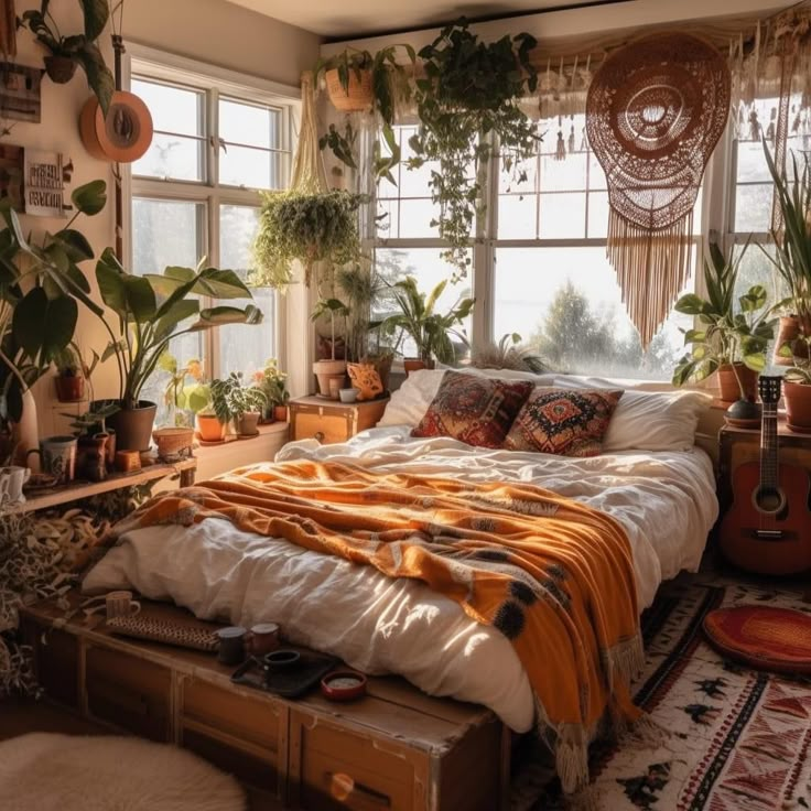 a bedroom with lots of plants in the window sill and a bed that has an orange blanket on it