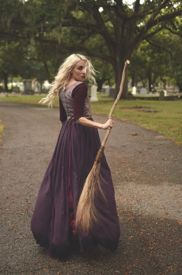 a woman in a long purple dress holding a broom