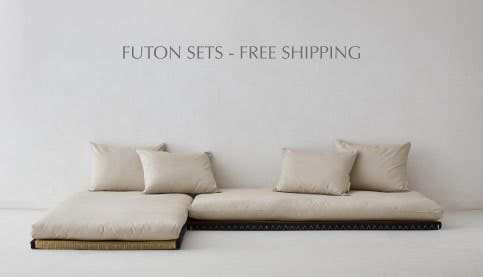 a white couch sitting on top of a wooden floor next to a sign that says futon sets free shipping