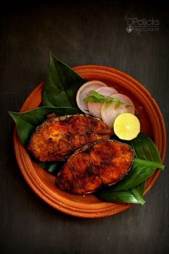 an orange plate topped with fried fish and onion slices on top of green leafy leaves