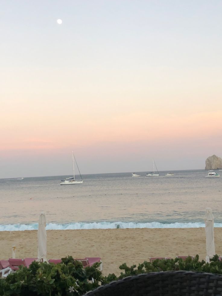 the beach is full of sailboats in the water at sunset or sunrise, and there are no people on it