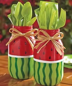 two mason jars filled with green leaves and red watermelon slices, tied with twine