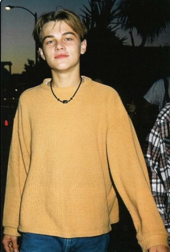 a young man wearing a yellow sweater and blue jeans