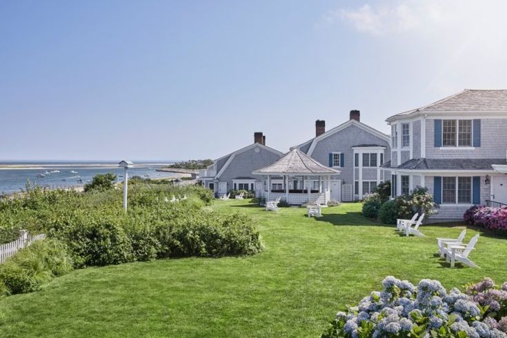 an oceanfront home with lawn chairs and flowers in the foreground