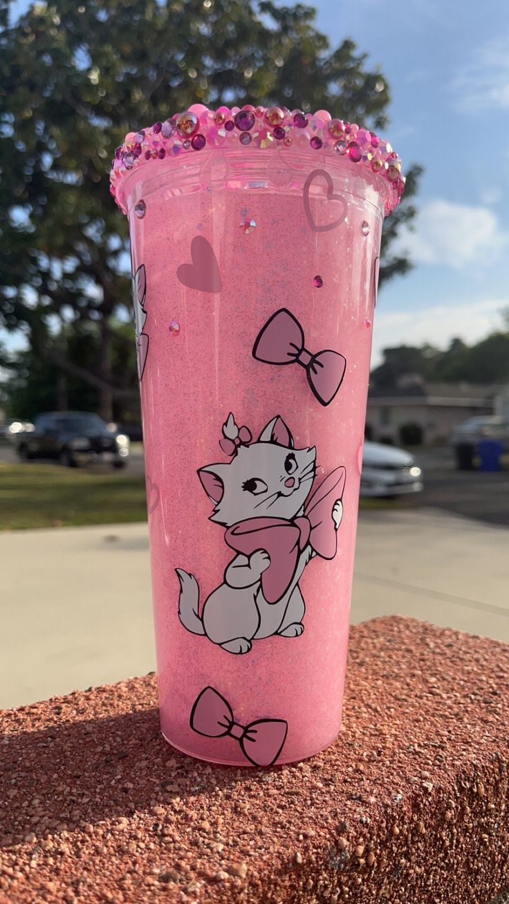 a pink cup sitting on top of a brick wall