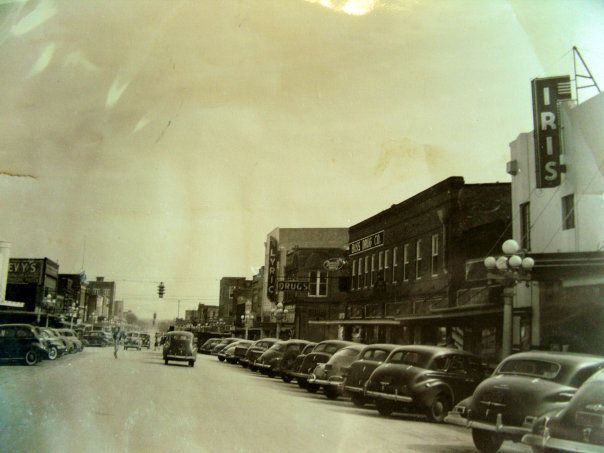 an old black and white photo of cars parked on the street