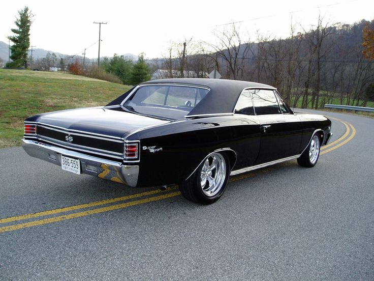 an old black car is parked on the side of the road