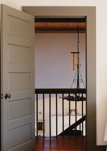 an open door leading to a bedroom with a bed in the corner and a lamp hanging from the ceiling