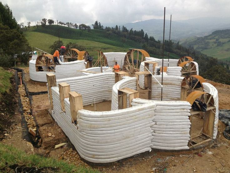 construction workers are working on the side of a hill with large white pipes and wooden posts