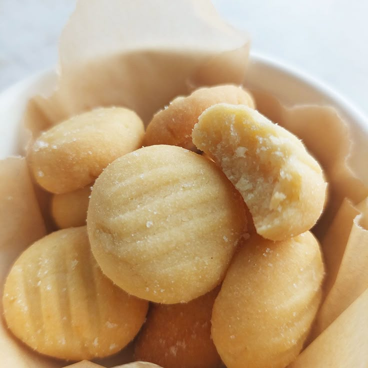 a white bowl filled with peeled bananas and powdered sugar on the top, sitting on a table