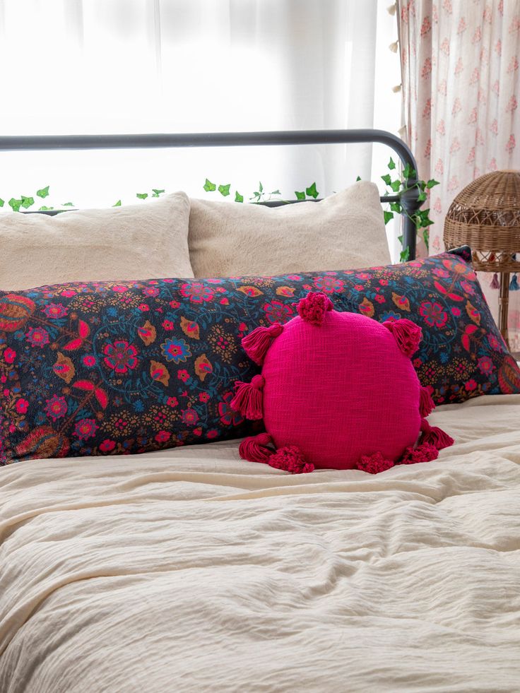 a pink pillow sitting on top of a bed