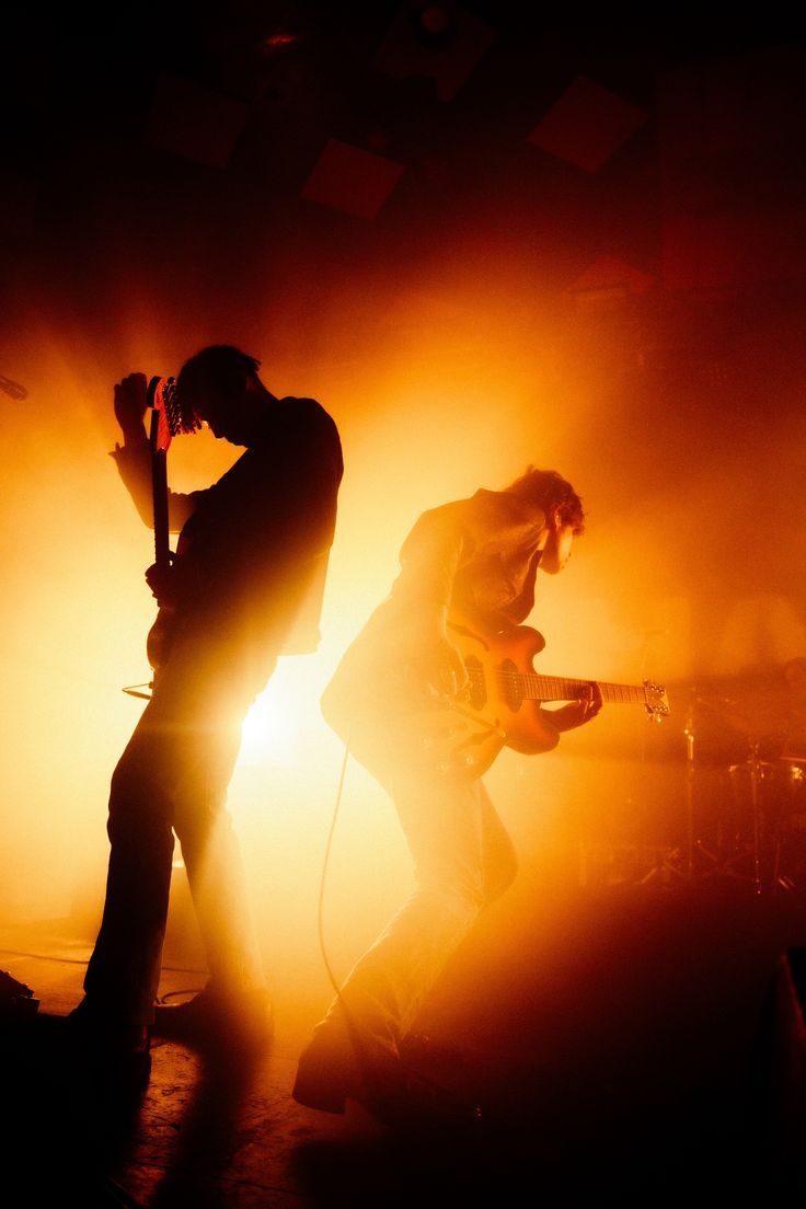 two people standing on stage with guitars in their hands