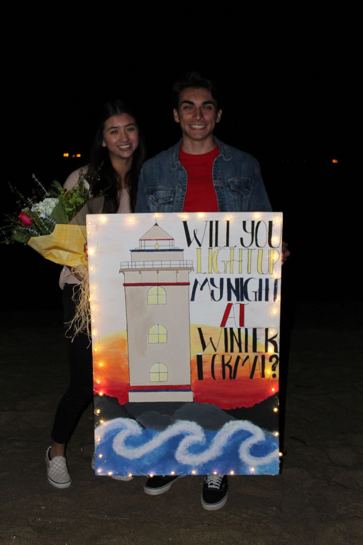 two people standing next to each other holding a light up sign with lights on it