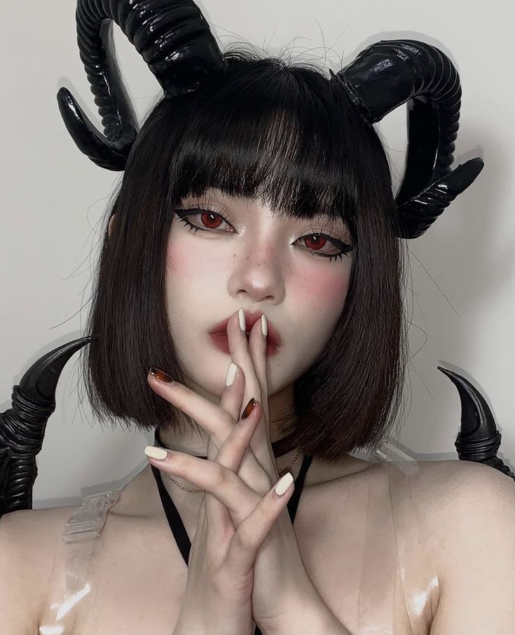 a woman with long black hair and horns on her head is posing for the camera