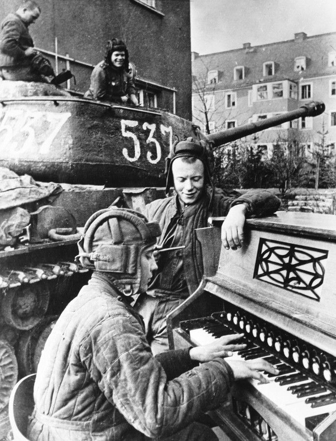 two men playing an organ in front of a tank