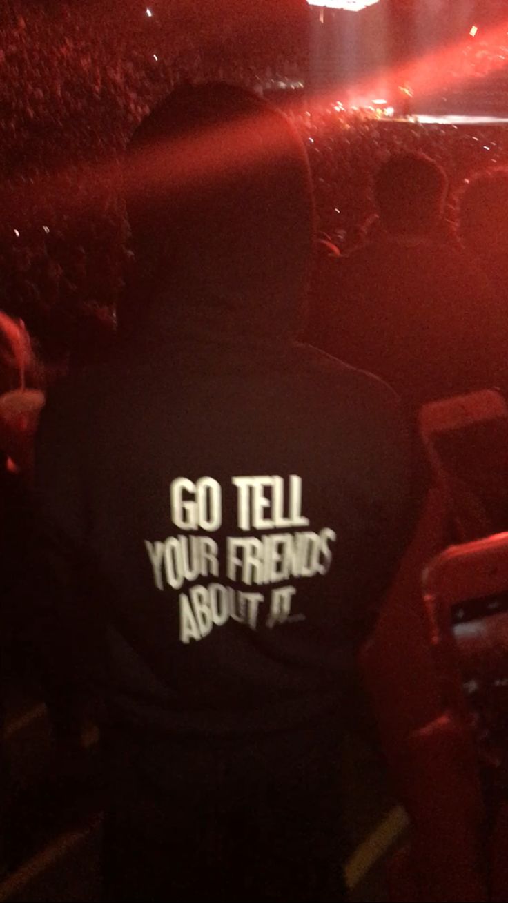 the back of a person wearing a black jacket with white writing on it at a concert