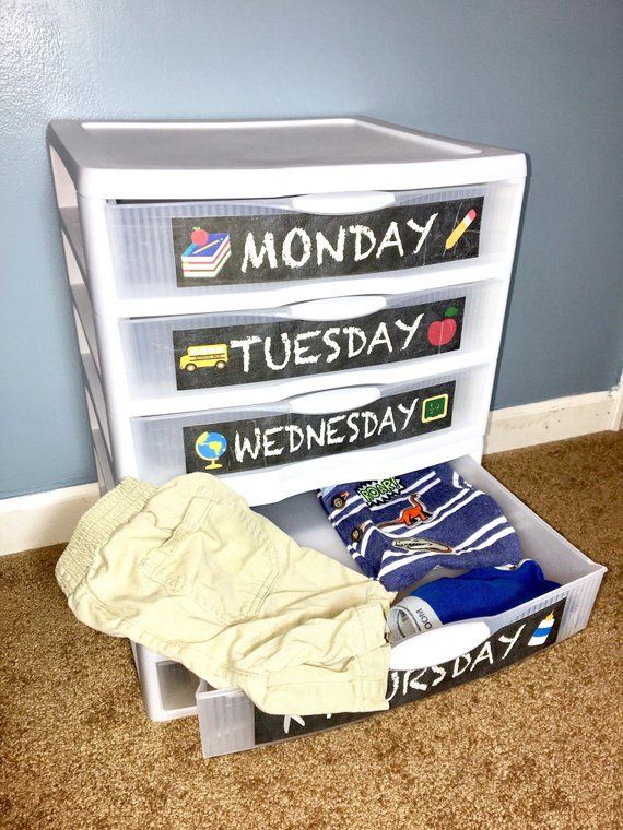 a white toy chest filled with clothes on top of a carpeted floor