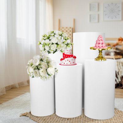 three white vases with pink and red cakes on them sitting in front of a dining room table