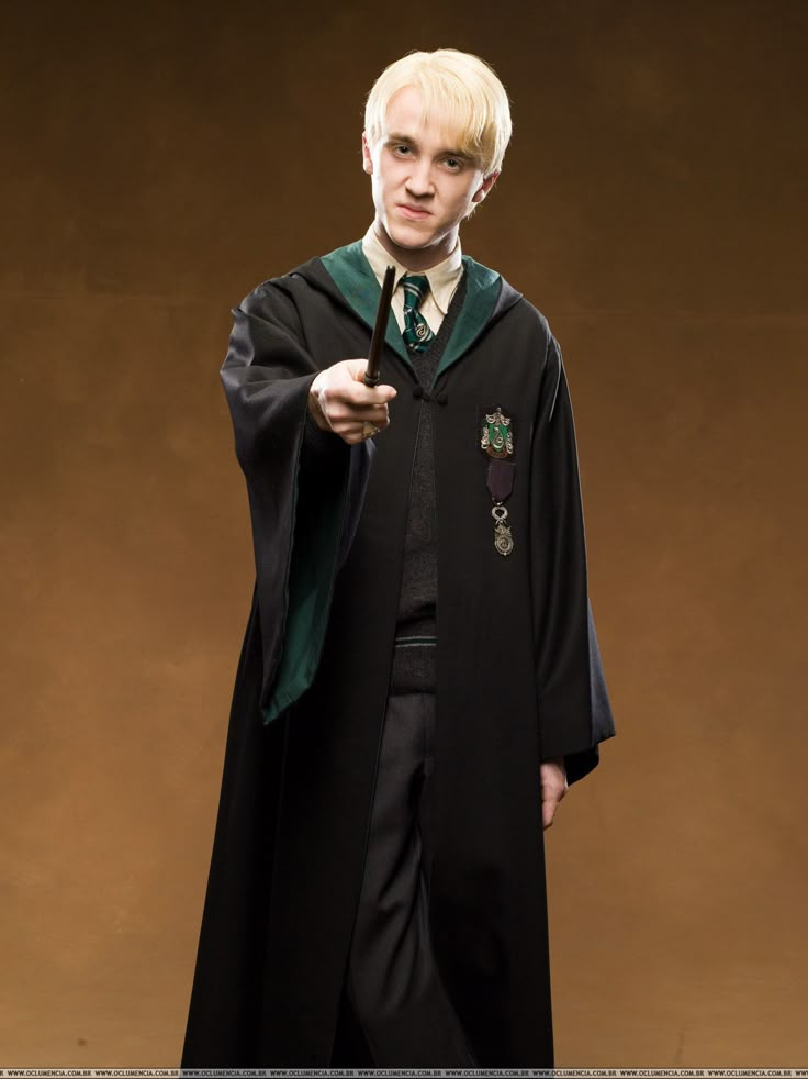 a man dressed as harry potter pointing to the side while wearing a black robe and green tie