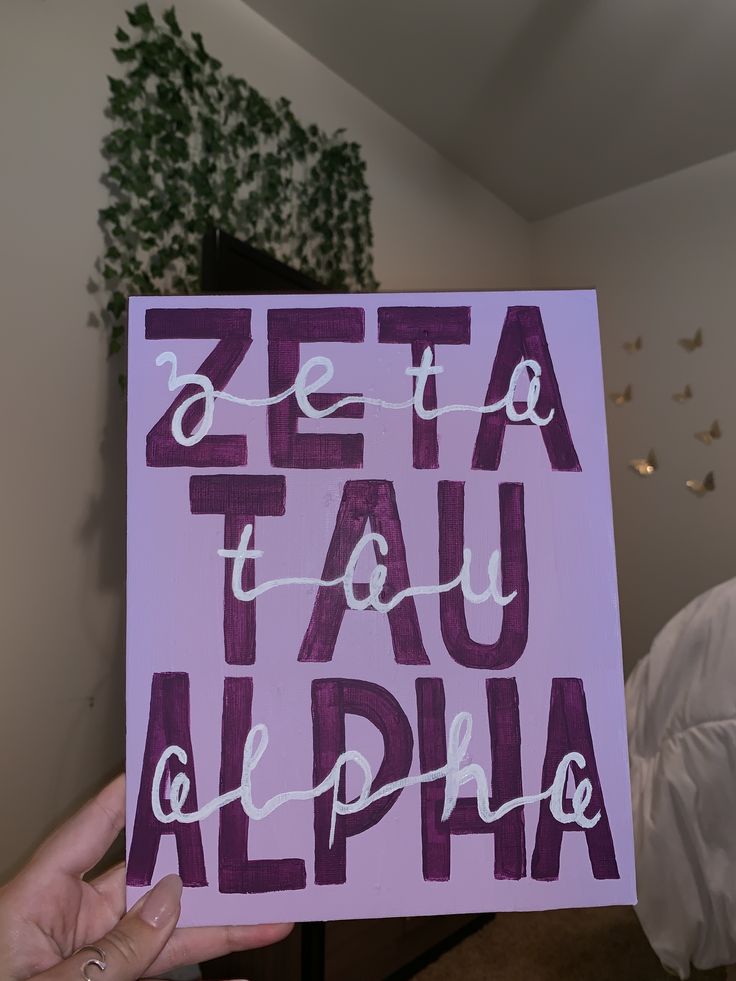 a person holding up a sign that says zefta tau alplha