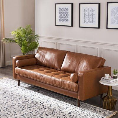 a brown leather couch sitting on top of a white rug