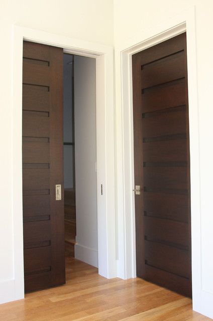 an empty room with two wooden doors and hard wood flooring on the other side