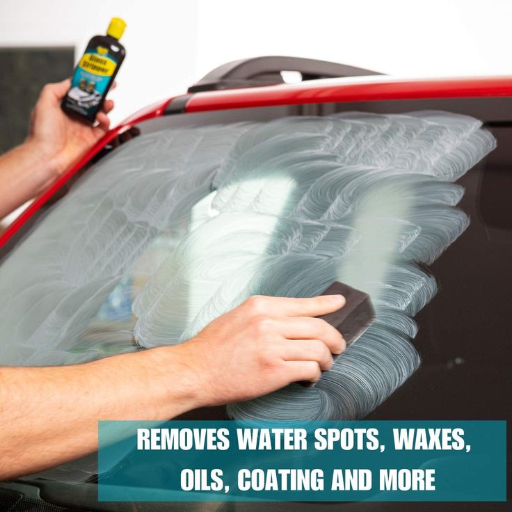 a man waxing the windshield of a car with an advertiser's hand