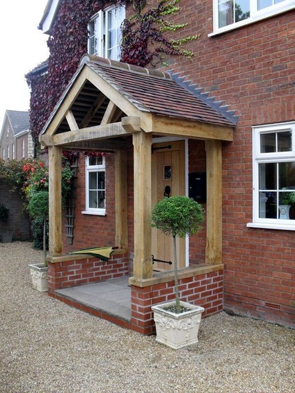 a wooden gazebo sitting in front of a brick building with potted plants on it