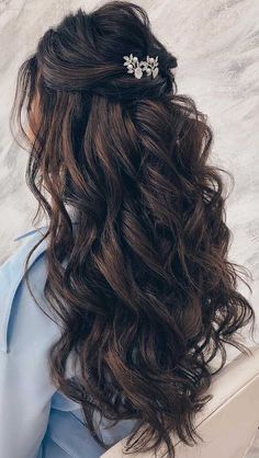 a woman with long hair wearing a blue dress and a flower clip in her hair