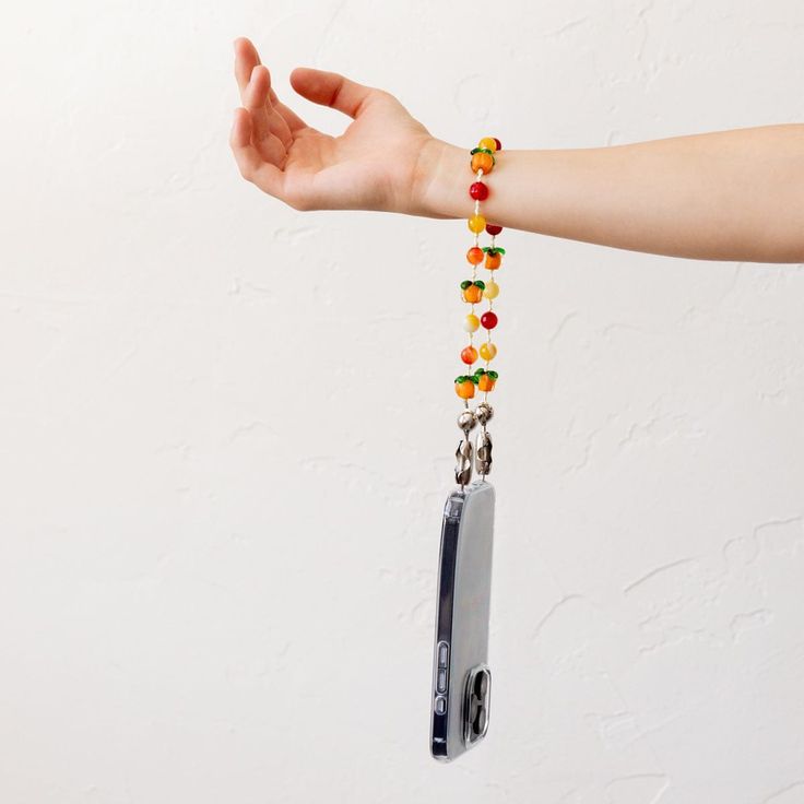 a person's hand holding onto a chain that has beads attached to it and an electronic device in the background